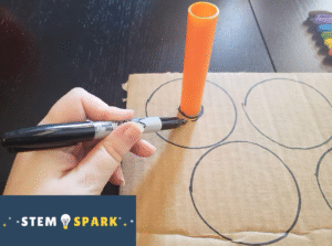 A hand tracing circles onto cardboard