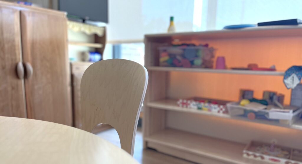 table, chair, and bookshelf with toys and learning materials on it