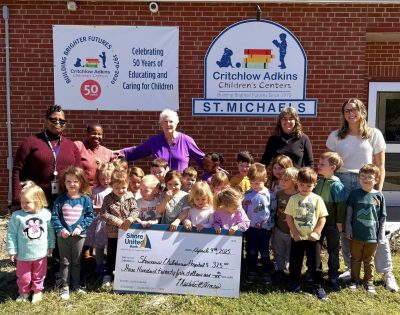 Group of children and adults posing with a big check